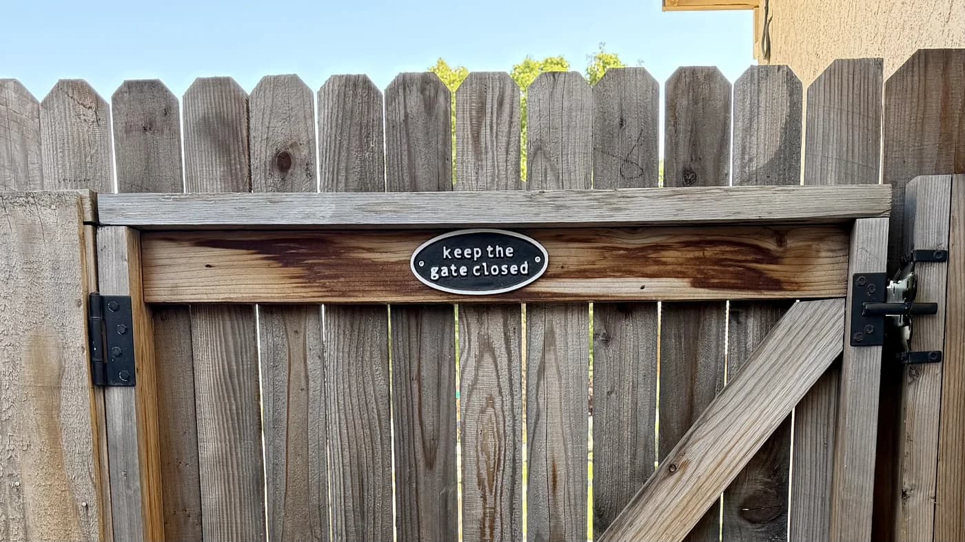 A closed wooden side gate with a sign reading keep the gate closed